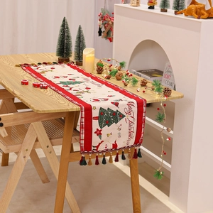 Close-up of Christmas table runner featuring festive prints and colorful fringe tassels
