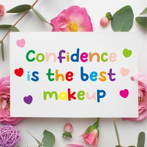 Close-up of decorative white card with colorful Confidence is the best makeup quote and flowers
