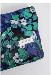 Close-up of floral jacquard fabric with H&R BAG logo label on a vintage pouch