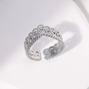 Macro detail of adjustable silver crown ring featuring intricate hollow lace patterns