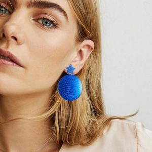 Blue disco ball earrings with star studs worn by a model in a retro fashion style