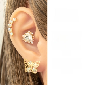 Detail shot of heart crystal stud and gold butterfly earring set worn on the ear