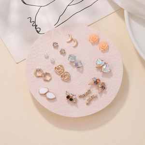 Close-up of golden earring set with pearls, zircons, and resin roses on a tray