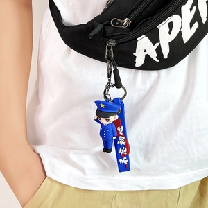 Cartoon policeman PVC keychain with salute pose on a black waist bag zipper