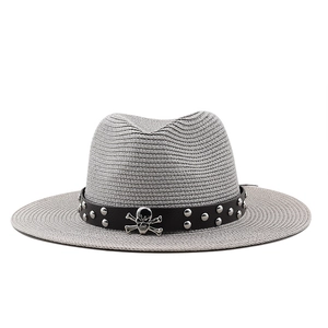 Detail of gray straw fedora with studded leather band and metallic skull ornament