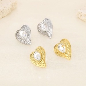 Dettaglio di orecchini a cuore con finitura testurizzata oro e argento e cristallo centrale