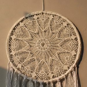 Close-up of white crochet dreamcatcher with intricate lace patterns and hanging tassels