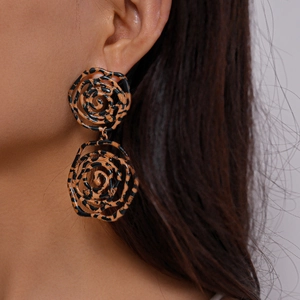 Close-up of leopard print spiral rose drop earrings worn by a model in vintage style