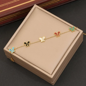 Détail d'un collier doré orné de cinq pendentifs papillons colorés posé sur son coffret
