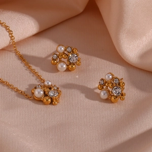 Macro view of gold flower necklace and earrings with pearls and zircon on silk
