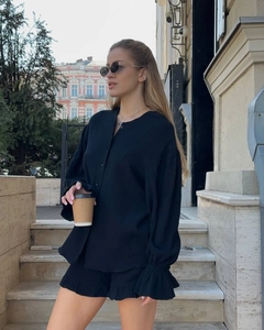 Détail d'un ensemble haut noir à manches longues et short à volants sur un mannequin dehors