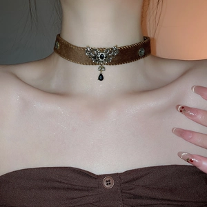 Close-up of vintage brown suede choker with ornate silver pendant and black teardrop gem