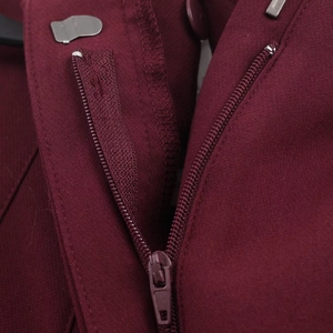 Detailed close-up of metal hook and zipper closure on burgundy straight-leg trousers