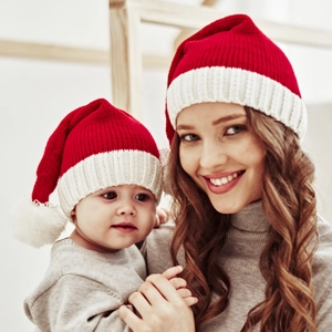 Close-up of mother and baby wearing matching red Christmas knit hats with white pompoms