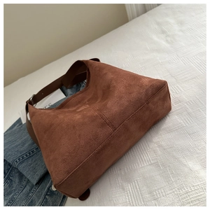Detailed close-up of brown suede hobo bag with a soft matte texture on white bedding