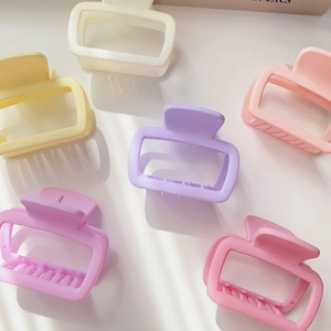 Flat lay of small square hollow hair claws in pastel pink, purple, and cream colors