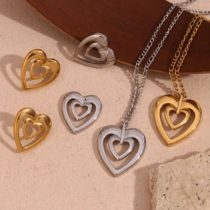 Detail of 18K gold and silver hollow heart jewelry set on a natural stone background