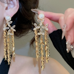 Detail of 18K gold plated flower fringe pearl earrings shown on a model's ear