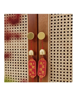 Detail of brass handle and red bell charm with lucky calligraphy on a wooden cabinet door