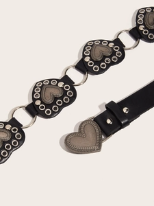 Dettaglio di cintura punk nera con toppe a cuore, anelli di metallo e rivetti