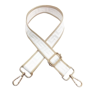 Detail of adjustable maze pattern bag strap with gold lobster clasps and jacquard texture