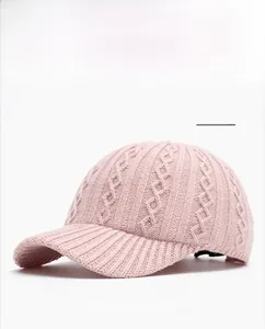 Detailed view of pink knitted baseball cap with soft cable knit texture and curved brim