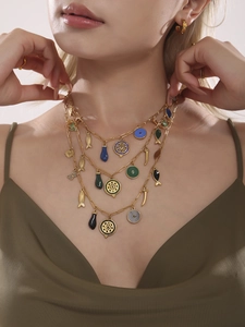 Détail du collier doré multicouche avec pendentifs colorés en forme d'œil et de poisson