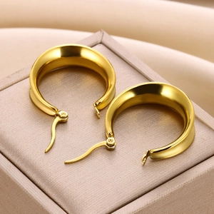 Detail of chunky gold curved geometric C-shape earrings resting on a jewelry box edge