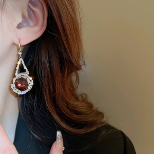 Gros plan d'une boucle d'oreille vintage en or avec pierre rouge et zircons sur un modèle