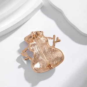 Golden snowman brooch back view with pin structure on a minimalist white background