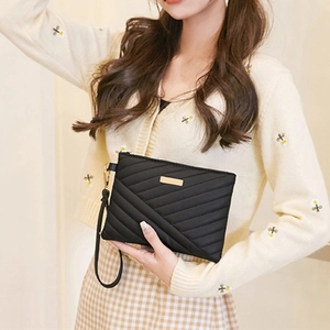 Detail of black quilted leather phone bag featuring V-shaped texture and gold hardware