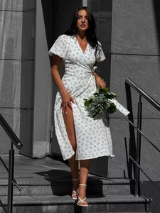 Detail of white floral cotton dress featuring puff sleeves and a side slit design