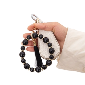 Porte-clés bracelet en perles avec pompon noir et mini pochette crème sur anneau