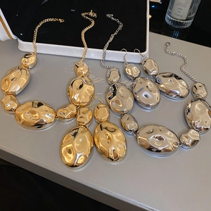 Close-up of gold and silver chunky hammered metal necklace and earrings jewelry set