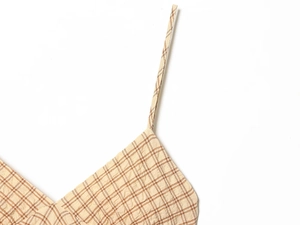Detailed view of plaid seersucker fabric texture and strap stitching on summer dress