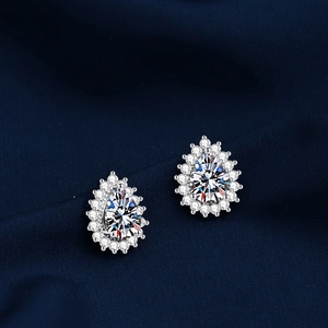 Macro shot of silver pear-shaped cluster stud earrings on elegant dark blue silk background