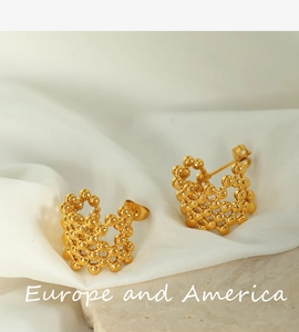 Detailed view of hollow golden spherical stud earring on soft white silk and stone