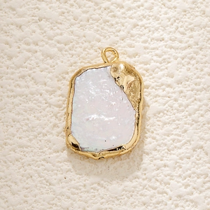 Macro shot of irregular baroque pearl pendant with textured gold-plated metal edges
