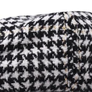Macro view of black and white houndstooth fabric with gold metallic thread details