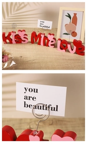 Detail of wooden letters KISS Mine Love with metal memo holders on a rustic table