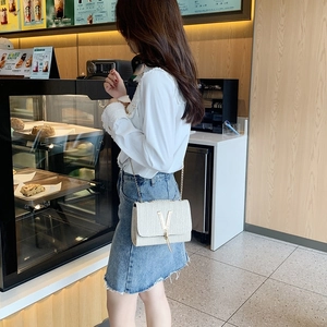 Stylish white woven chain shoulder bag with gold V-shaped logo and elegant metal strap