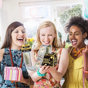 Women celebrating with a black and gold happy birthday money pull out box at a party