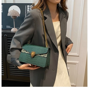 Detail of green croc-embossed shoulder bag with golden lion head buckle and chain strap