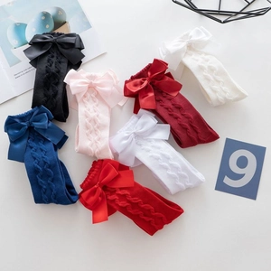 Detail of cable knit toddler socks featuring large satin bows in multiple colors