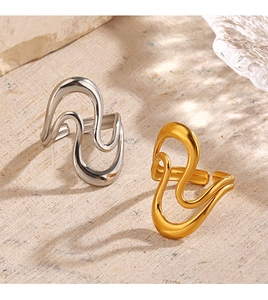 Detail of wavy 18K gold and silver plated stainless steel rings on a stone surface