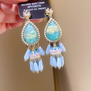 Macro shot of 925 silver fringe earrings with blue crystal and hanging beaded tassels