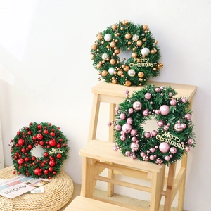 Three artificial Christmas wreaths with ornaments and Merry Christmas sign on wooden stairs