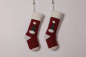 Detail of red knitted Christmas stockings with green hat patterns and white plush accents