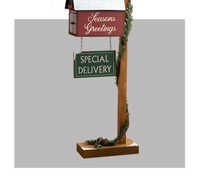 Close-up of wooden Christmas mailbox ornament with pine needles and snowy details