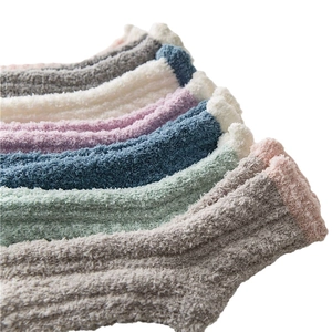 Stack of colorful thick coral fleece socks in grey white pink and blue for winter